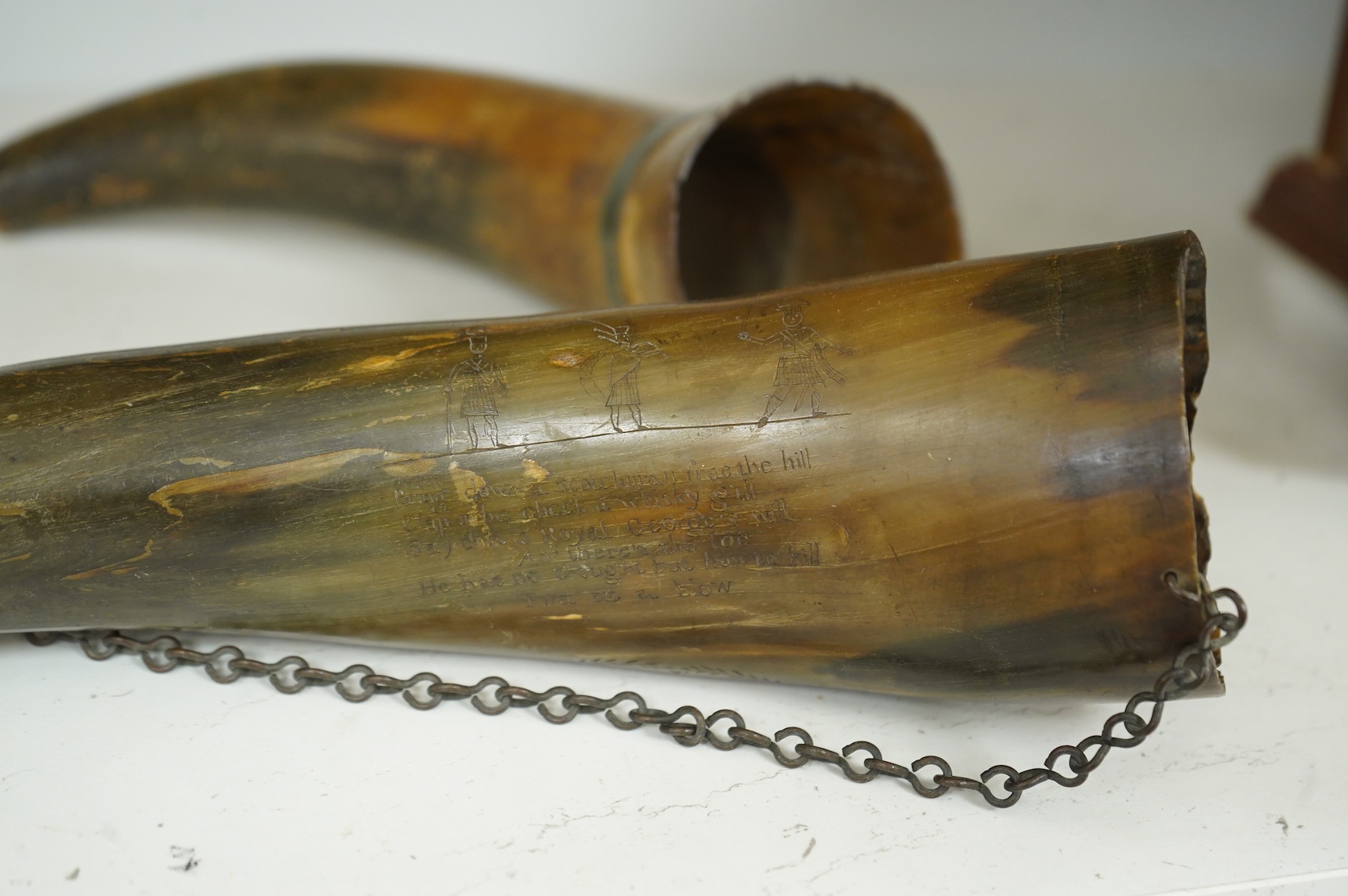 Two scrimshaw engraved cowhorn flasks the first engraved with ships, plants, fish, an anchor, a watering can and various other implements, the second engraved with a Scottish sentimental verse and the owner’s name; D. Fi